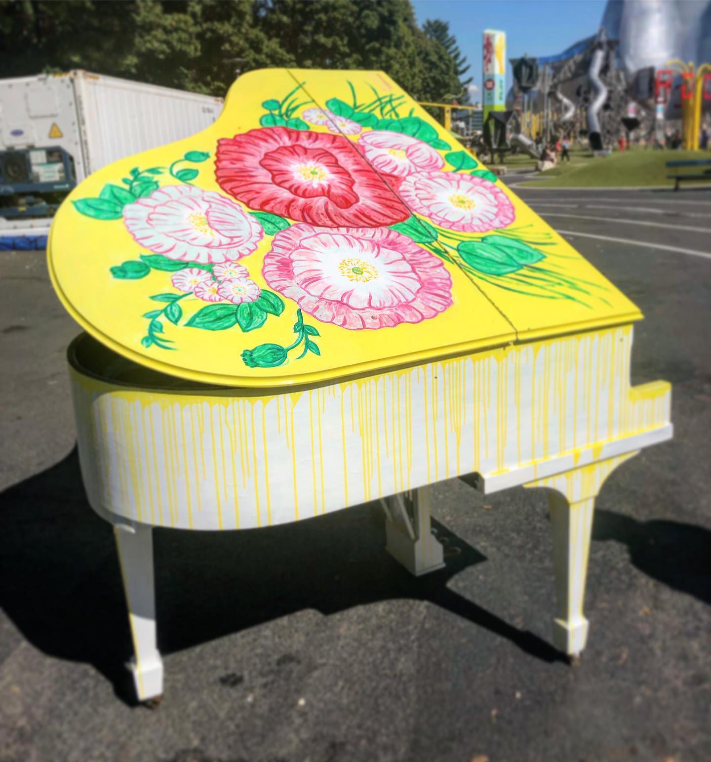 A yellow public piano painted with large flowers at Seattle Center